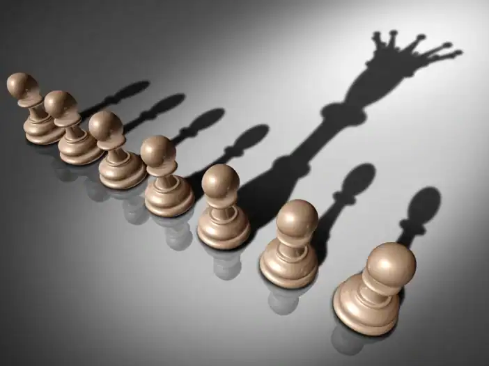 Chess pawns casting shadows on a grey surface, with the shadow of a king for one piece
